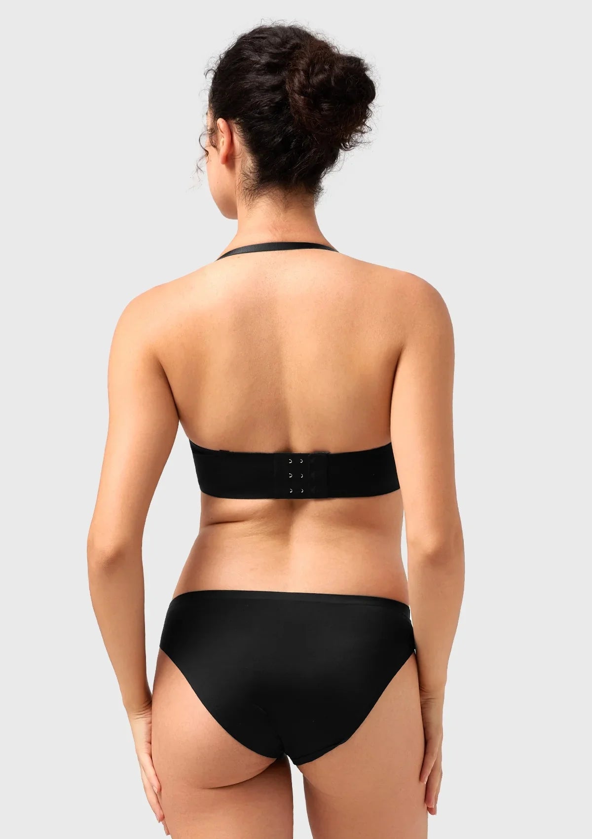 Back view of the black convertible bra worn in a chic halter style, offering reliable lift and adaptability for unique necklines.