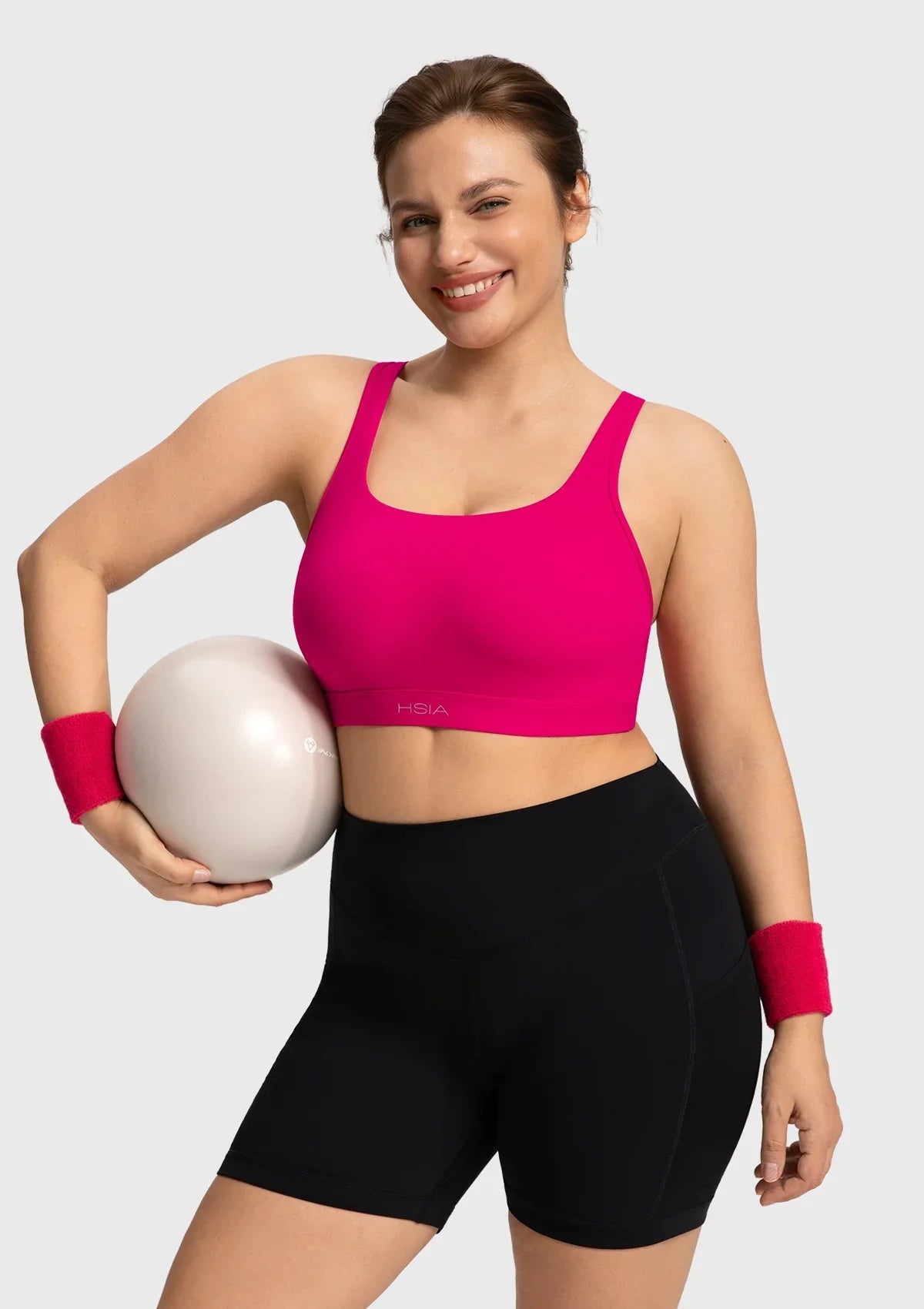 Active woman stretching in the dragon fruit pink Aura sports bra showing fluid mobility