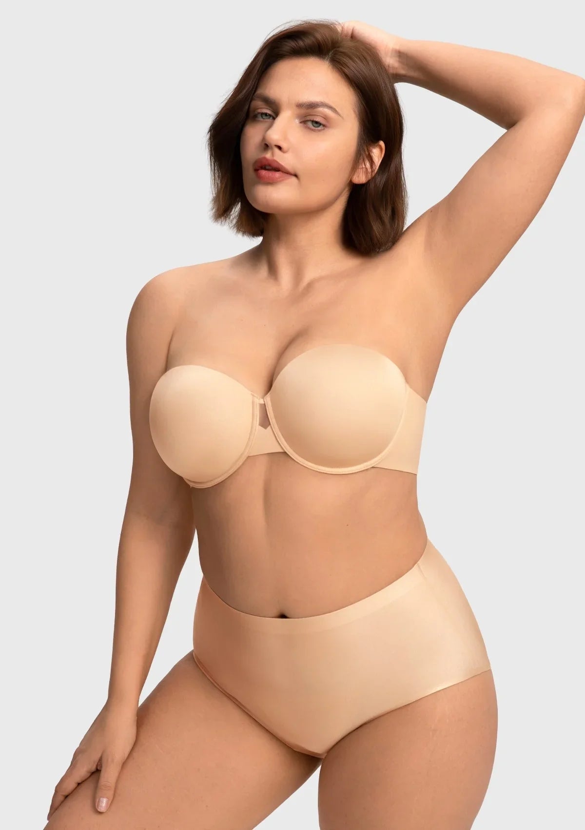Smiling woman raising her arms freely in the nude no-slip strapless bra, demonstrating unwavering support without any silicone irritation.