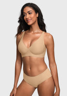 A woman modeling a matching light beige bra and high-waisted brief set against a light gray studio background.