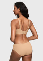 A woman shown from the back wearing a light beige seamless bra and matching high-waisted briefs against a light gray studio background.