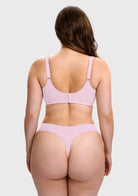A woman shown from the back wearing a light pink two-piece lingerie set, consisting of a bralette with adjustable shoulder straps and matching high-cut thong bottoms, against a solid light gray background.